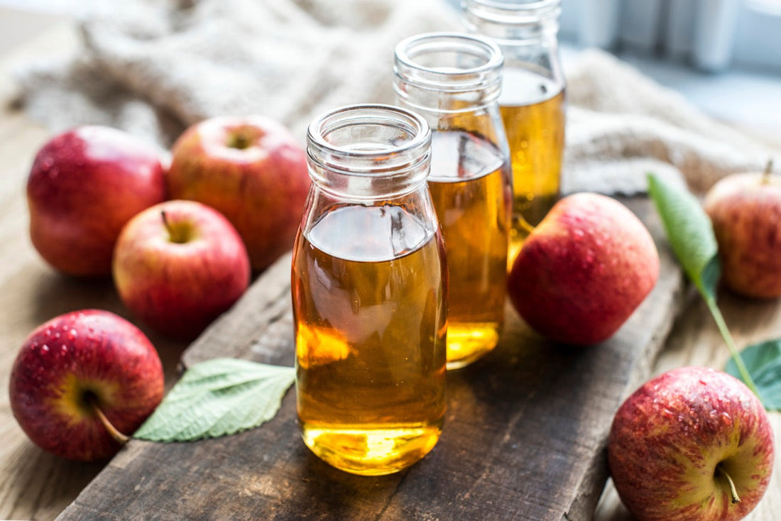 Äppelcidervinäger i glas och äpplen runt om kring