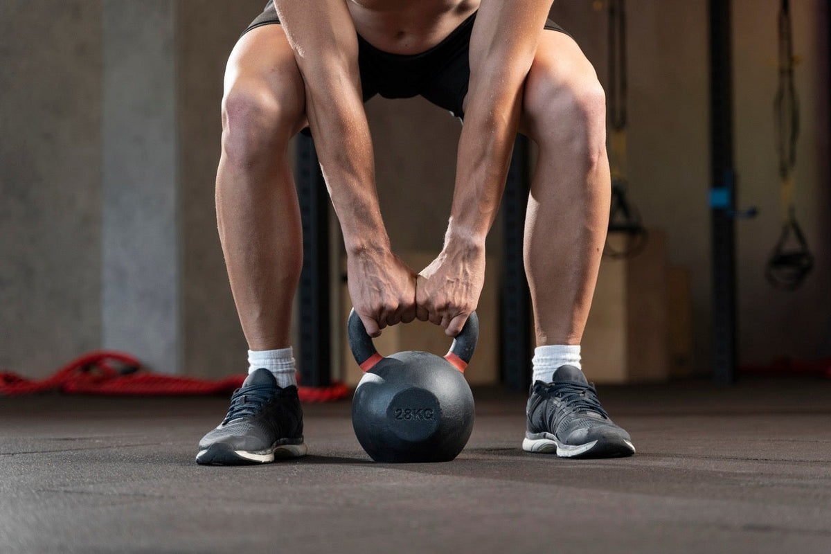 Man som greppar en kettlebell på marken för att träna