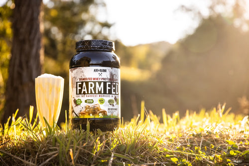 Axe & Sledge Farm Fed vassleproteinisolat i burk med svart lock, står i gräs